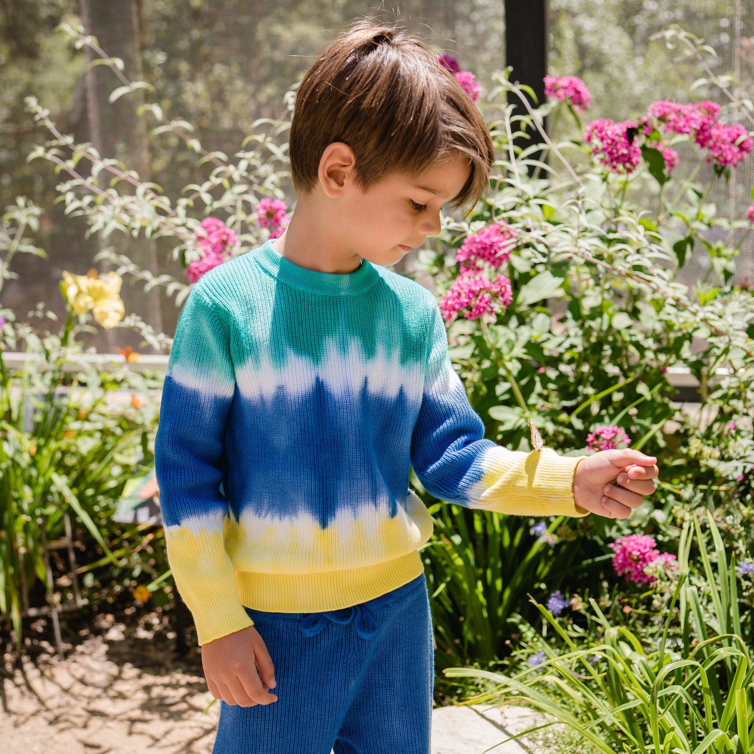 Boy wearing green, blue and yellow dip die sweater.